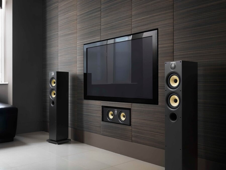 Two B&W high-end standing speakers on either side of a large TV screen.