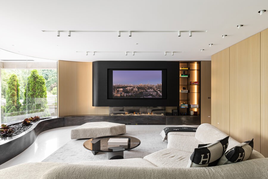 A living room area of the Iceberg home project, a modern couch and TV setup, with a large wall window to the left.