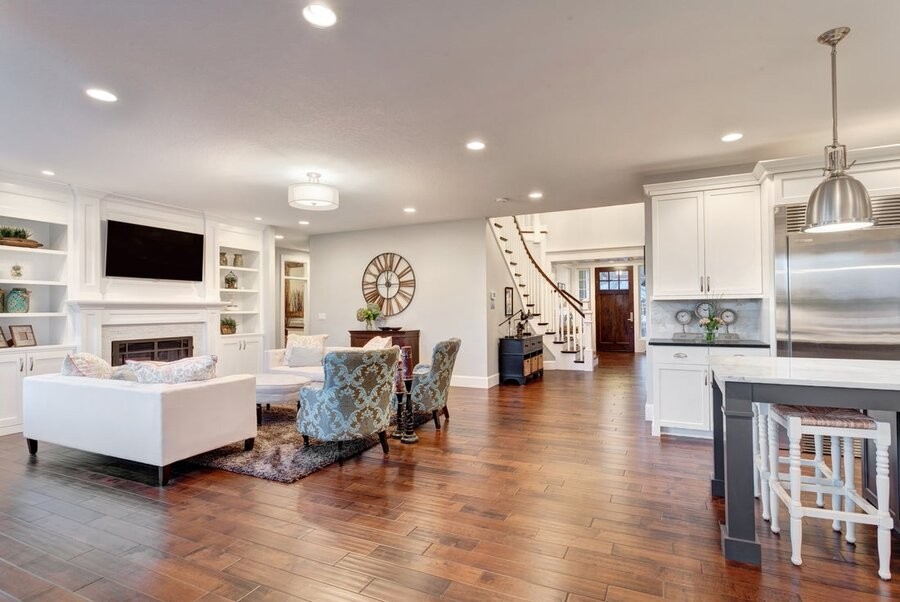 An open living space connecting a family room and kitchen with a foyer and front door in the background.