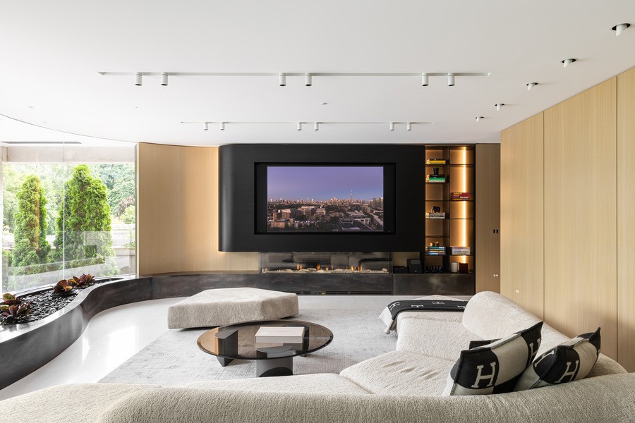 An open living space featuring ceiling speakers, a wall-sized window, and a large couch.